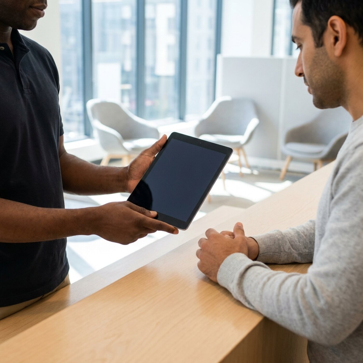 Two people looking at a tablet across a counter.