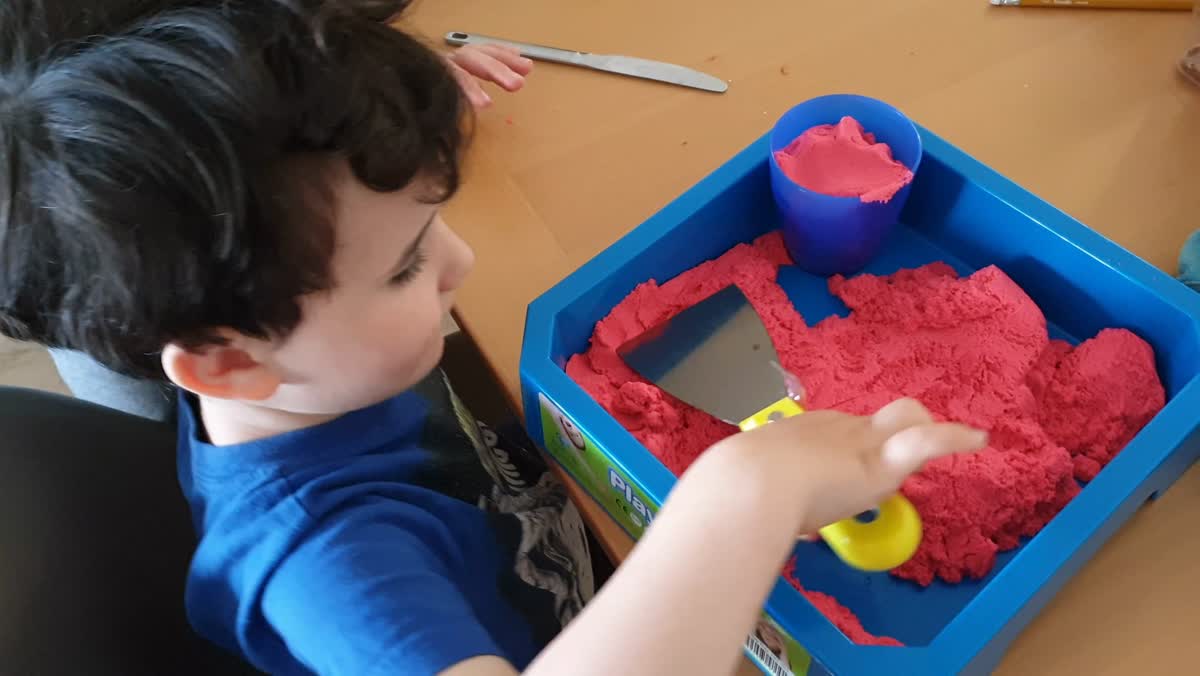 A young child's hands working in kinetic sand during a sensory session