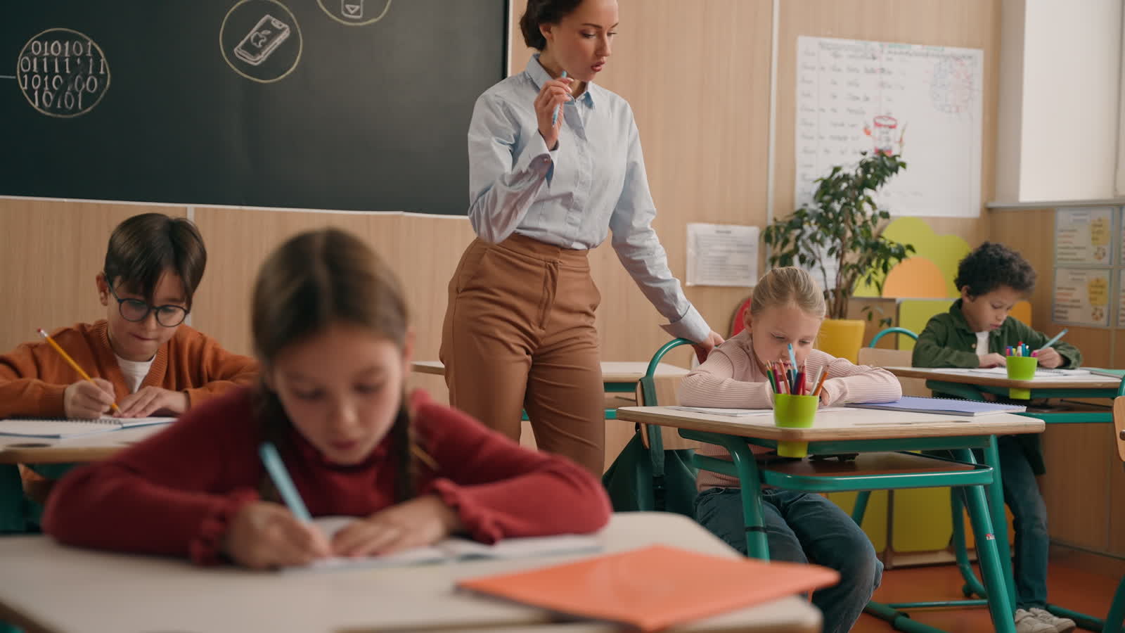 A teacher moving between desks supporting students during a writing lesson