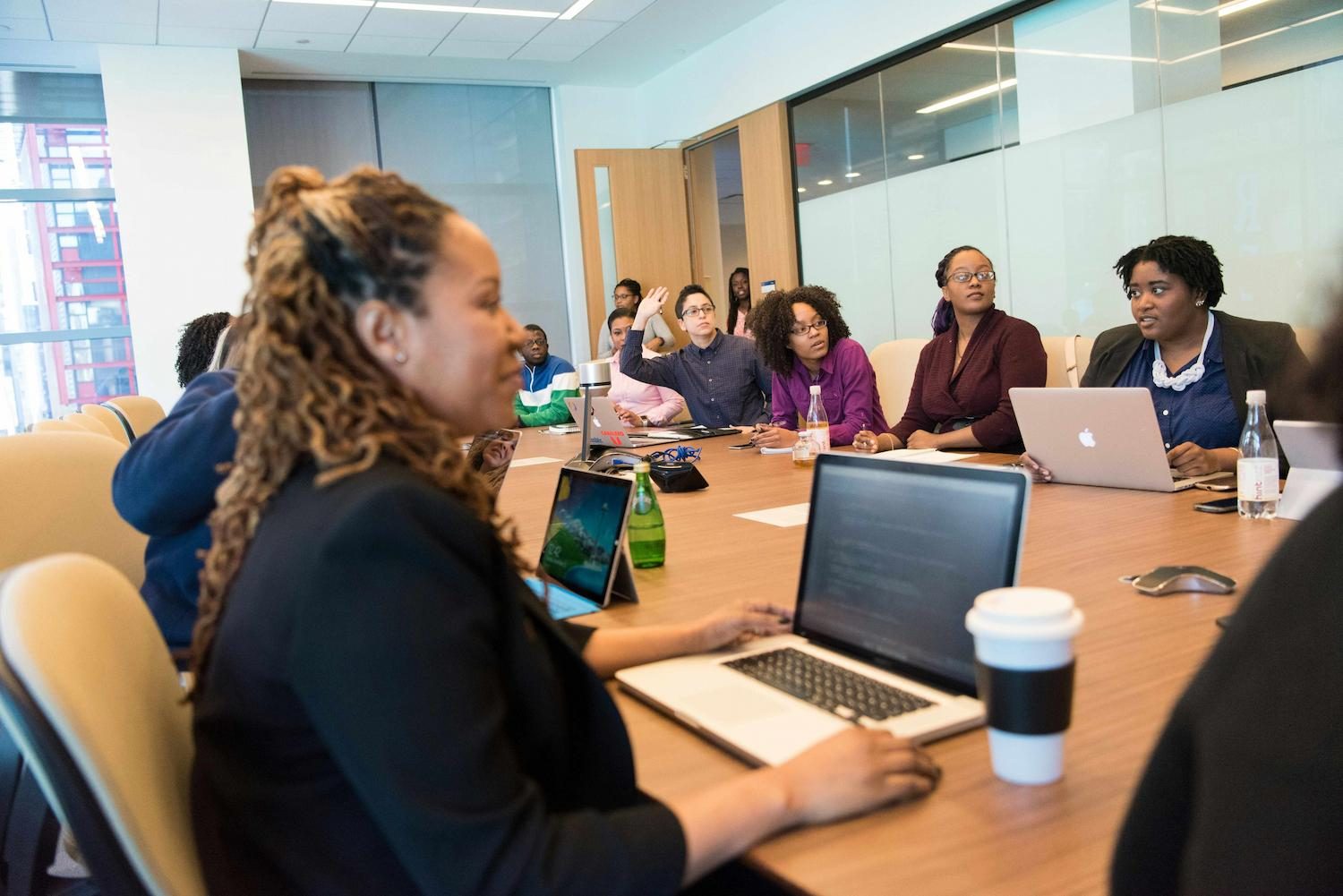 A team meeting around a conference table with laptops open