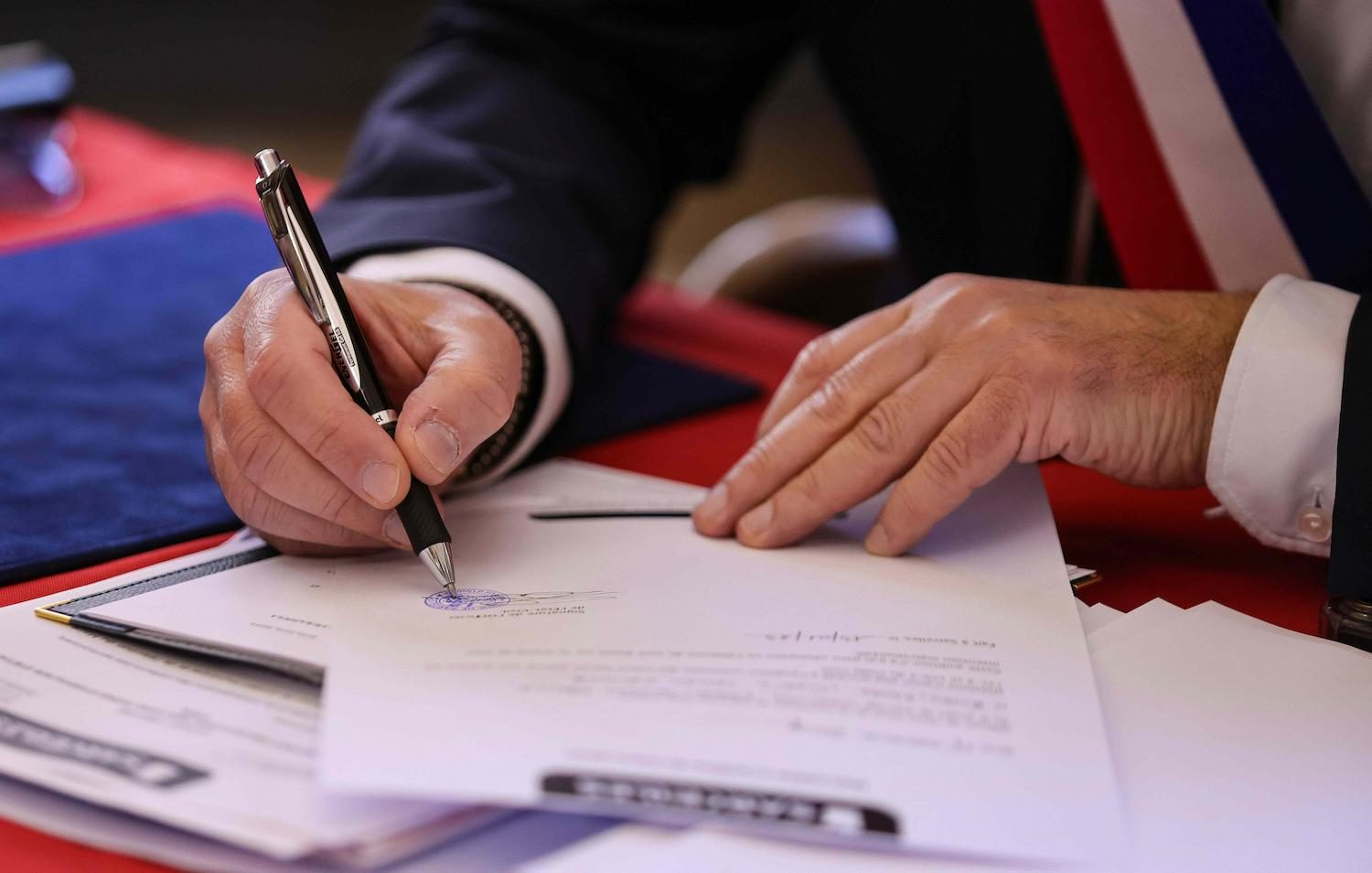 A person signing a stamped document with a pen
