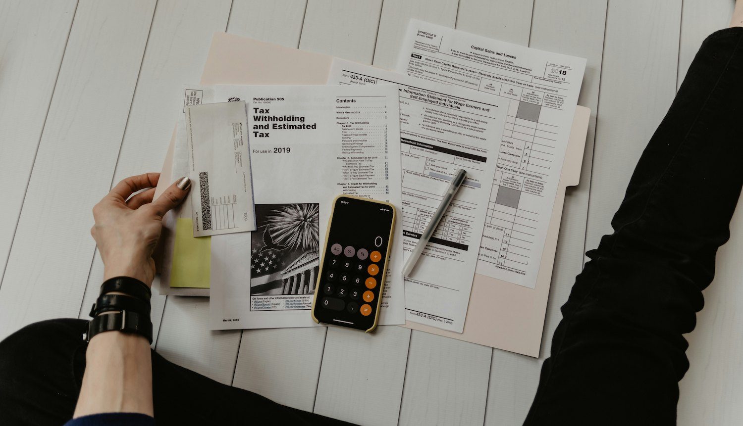 Tax and financial forms spread out beside a calculator and a pen