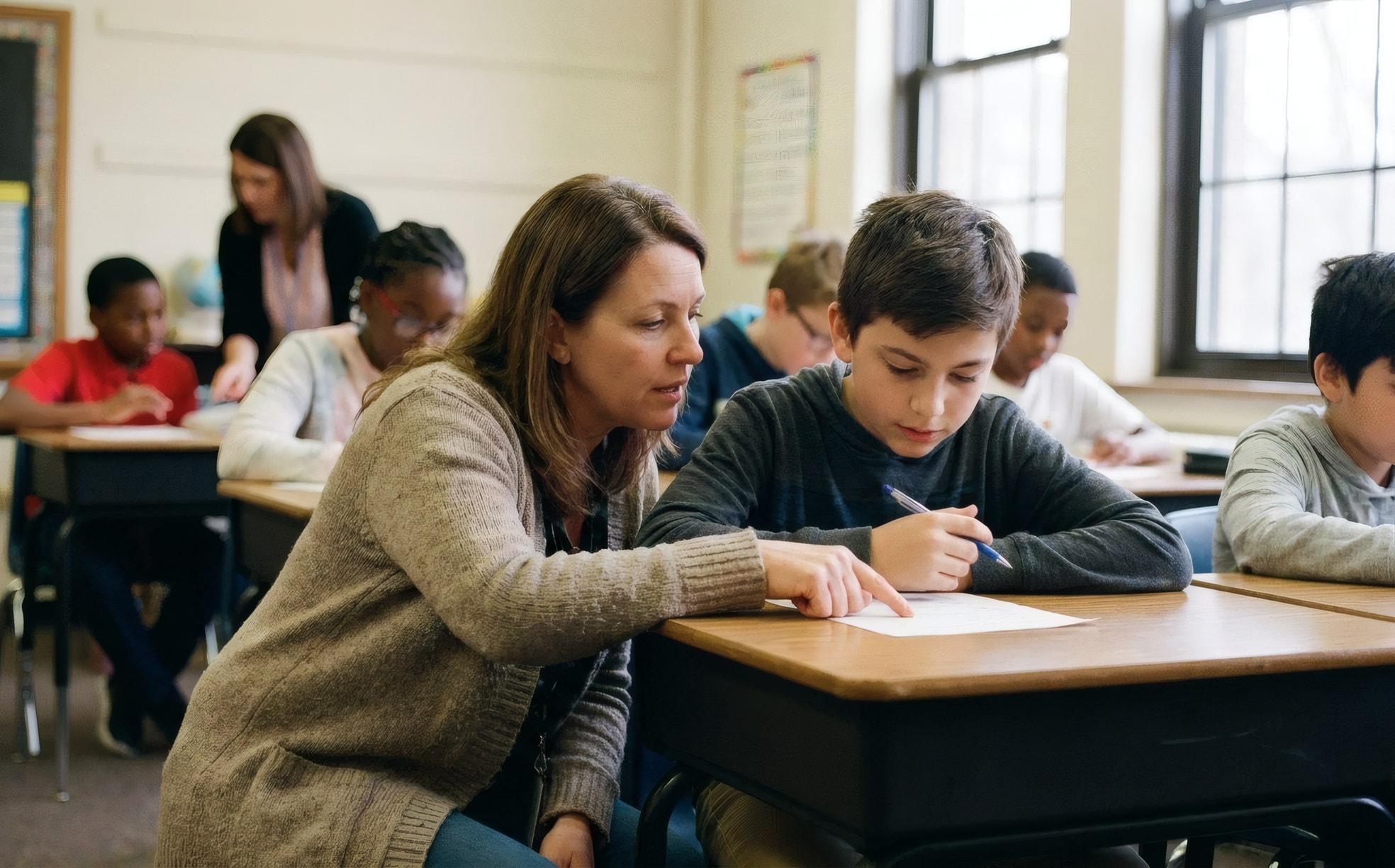 An adult helping a child with schoolwork in a classroom